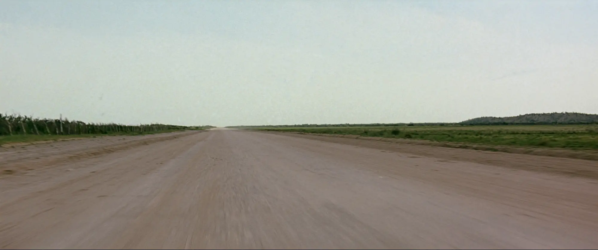 A straight caliche road running across flat open Texas land toward the horizon.